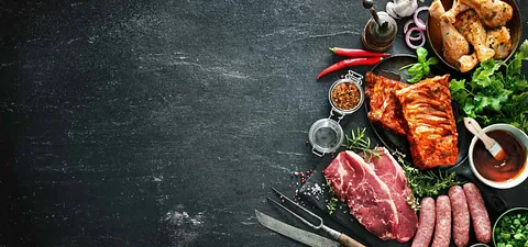 Schieferplatte mit Fleisch, Gewürzen, Messern und anderen Artikeln.